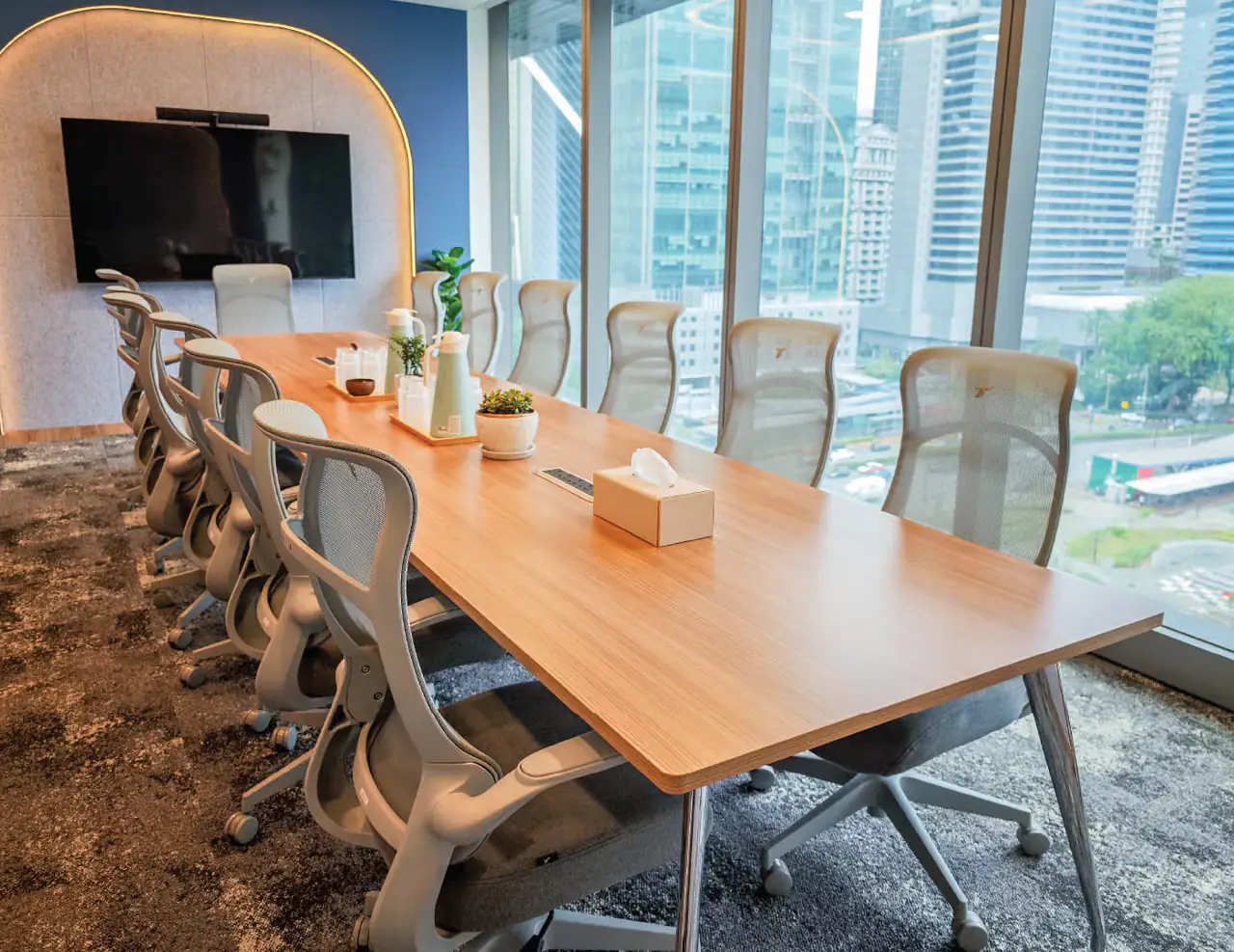 A WORQ boardroom set for twelve, with a city view through floor-to-ceiling windows